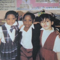 three children posing for a picture in a classroom
